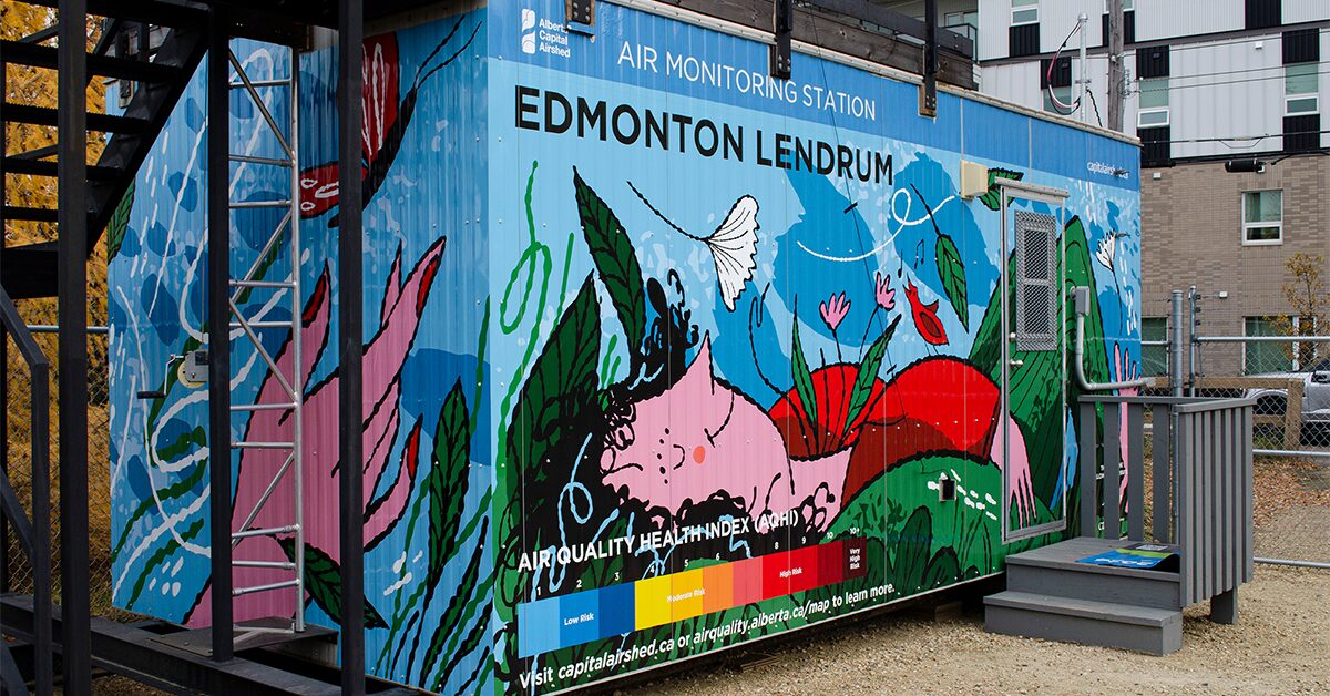 Lendrum Air Monitoring Station in Edmonotn, Alberta, wrapped in artwork by Amanda Schutz depicting an adult woman laying blissed out in grass, surrounded by leaves and flowers.